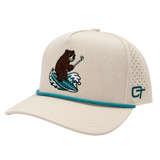 A beige baseball cap with a turquoise embroidered design of a bear surfing on the front, a turquoise band around the visor, and a perforated side panel with a teal CT logo.